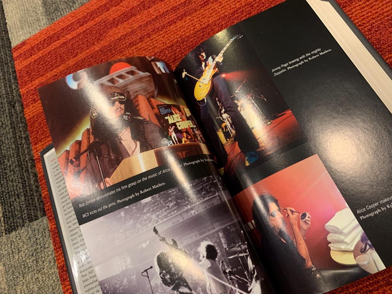 Puede incluir: Libro abierto con fotograf&iacute;as de conciertos de Rob Zombie, Jimmy Page y Alice Cooper. El libro est&aacute; sobre una superficie con estampado rojo y gris. El texto incluye "MCS kicks out the jams" y cr&eacute;ditos del fot&oacute;grafo.