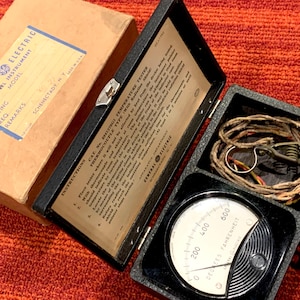 May include: Vintage General Electric panel instrument in a black case. The case is open, revealing a gauge with a needle and the text "DEGREES FAHRENHEIT". The box also contains a coiled wire and the original instructions.