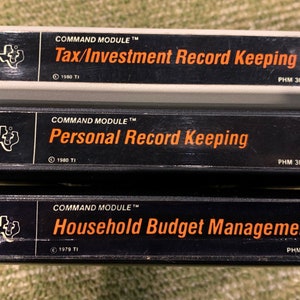 May include: Three black and white cartridges for the Texas Instruments TI-99/4A home computer. The cartridges are labeled "Command Module" and feature the titles "Tax/Investment Record Keeping", "Personal Record Keeping", and "Household Budget Management".