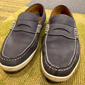 May include: A pair of dark blue leather loafers with white stitching and a white rubber sole.