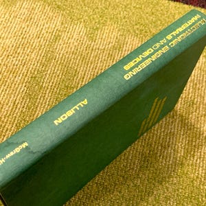 May include: A green hardcover book with gold lettering on the spine. The title is "Electronic Engineering Materials and Devices" by Allison. The book is published by McGraw-Hill.