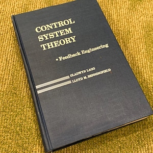 May include: A blue hardcover book titled "Control System Theory - Feedback Engineering" by Gladwyn Lago and Lloyd M. Benningfield.