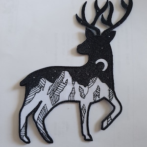 Op de afbeelding: Zwart-witte geborduurde patch van een hert met een bergketen en een halve maan in zijn silhouet.