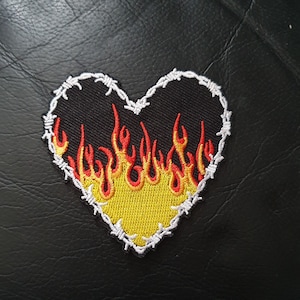 May include: A black heart-shaped patch with a barbed wire border and yellow and red flames inside.