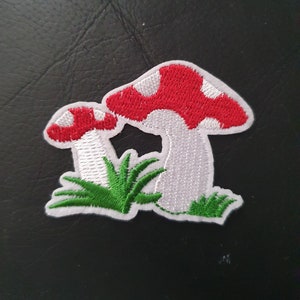 May include: White and red embroidered mushroom patch with green grass.