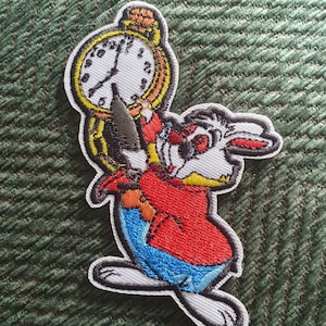 May include: White rabbit holding a large gold pocket watch with black Roman numeral markings. The rabbit is wearing a red jacket, blue trousers, and a white shirt. The rabbit has red eyes and a black nose.