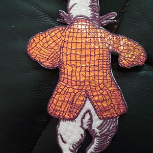 May include: Embroidered patch featuring a rabbit in a checkered orange jacket, purple accents, and white fur. The rabbit has long ears with purple tips and is in a running pose. This patch is suitable for clothing or accessories.