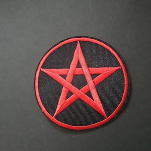 Puede incluir: Un pentagrama rojo bordado en un parche circular negro.