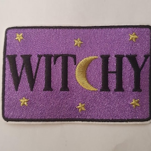 May include: Purple embroidered patch with the word "Witchy" in black lettering, a crescent moon, and gold stars.