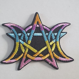 May include: Embroidered patch featuring a colorful, stylized design. The patch has a black background with a central star shape and intertwined crescent moon shapes. The design incorporates yellow, orange, pink, blue, and purple threads.
