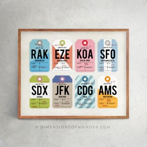 May include: A framed print featuring eight colorful vintage-style luggage tags. Each tag displays a different airport code and destination, including Marrakech, Buenos Aires, and San Francisco. The tags are arranged in a grid pattern.