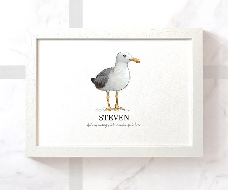 Op de afbeelding: Een wit ingelijst print met een aquarel-illustratie van een meeuw. De meeuw staat op een witte achtergrond. De naam "STEVEN" staat onder de meeuw. De tekst "Voeg een bericht, datum of aangepaste quote hier toe" staat onder de naam.