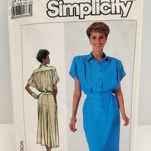 May include: Simplicity sewing pattern number 7942 for a dress. The pattern includes two views: a short-sleeved dress with a button-up front and a skirt with a gathered waist, and a long-sleeved dress with a button-up front and a skirt with a gathered waist. The pattern is for sizes N (10-12-14) and EUR. N(38+40+42).