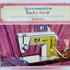 Może przedstawiać: Różowe i białe pudełko z tekstem "Accessories Touch & Sew" i "DELUXE ZIG-ZAG SEWING MACHINE/MODEL 635 SINGER" z przodu. Pudełko zawiera zdjęcie białej maszyny do szycia z żółtym panelem sterowania.