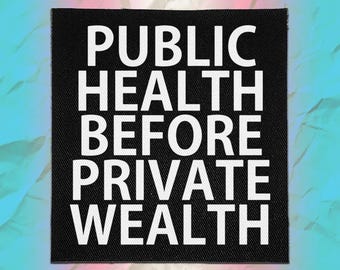 May include: A square black fabric patch featuring the white text "PUBLIC HEALTH BEFORE PRIVATE WEALTH" in a bold, sans-serif font. The patch has a visible woven texture and clean, straight edges, presenting a clear and high-contrast design.