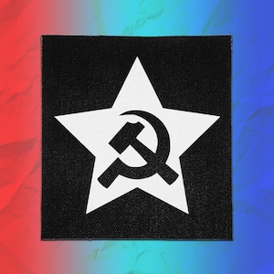 May include: A square-shaped black fabric patch featuring a large white five-pointed star centered on the surface. Inside the white star, there is a black graphic symbol consisting of a crossed hammer and sickle, creating a high-contrast design.