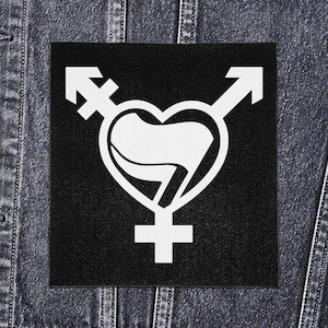 Op de afbeelding: Een zwarte vierkante patch met een wit transgender pride-symbool. Het ontwerp bevat een hartvorm met een transgender vlag, mannelijke en vrouwelijke symbolen en pijlen. De patch wordt getoond op een spijkerjasje.