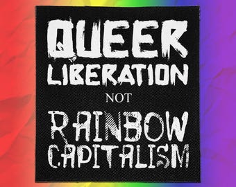 May include: A square black fabric patch featuring white distressed-style text that reads QUEER LIBERATION NOT RAINBOW CAPITALISM. The lettering is arranged in four lines with the words QUEER and RAINBOW CAPITALISM in a larger, bold font.