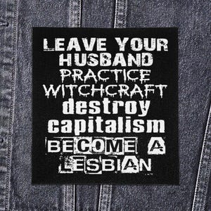 May include: Black square patch with white text that reads "LEAVE YOUR HUSBAND PRACTICE WITCHCRAFT DESTROY CAPITALISM BECOME A LESBIAN". The patch is on a denim jacket.