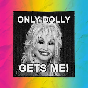 May include: A square black fabric patch featuring a white halftone portrait of a person with voluminous hair. The text "ONLY DOLLY" is printed in white capital letters above the portrait, and "GETS ME!" is printed in white capital letters below.