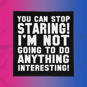 May include: A square black fabric patch featuring bold white text that reads: YOU CAN STOP STARING! I'M NOT GOING TO DO ANYTHING INTERESTING! The patch has a visible woven texture and clean, straight edges, presenting a high-contrast graphic design.