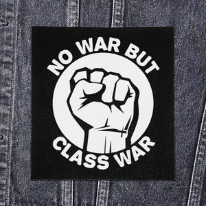 Könnte beinhalten: Schwarzer quadratischer Aufnäher mit einem weißen Faustmotiv in einem weißen Kreis, umgeben von den Worten "NO WAR BUT CLASS WAR" in Weiß. Der Aufnäher ist für Kleidung oder Accessoires gedacht und setzt ein klares Statement. Der Hintergrund ist Denim.