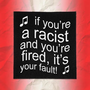 May include: A square black fabric patch featuring white text that reads, "if you're a racist and you're fired, it's your fault!" with a musical note symbol at the top left and bottom right corners, set against a textured background.