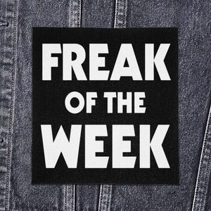 Puede incluir: Parche cuadrado negro con el texto "FREAK OF THE WEEK" en letras blancas en negrita. El parche está colocado sobre una chaqueta vaquera oscura.