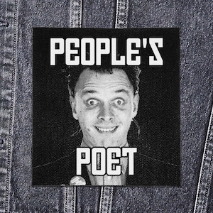May include: A monochrome patch featuring the words "PEOPLE'S POET" and a smiling man's face. The patch is rectangular and likely made of fabric, designed to be sewn onto clothing or bags. The image is set against a dark background.