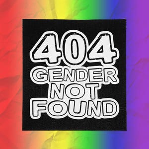 May include: A square black patch featuring white text that reads 404 GENDER NOT FOUND. The lettering is bold and has a distressed, outlined style. The patch has a visible fabric texture and is set against a vibrant, multi-colored rainbow background.