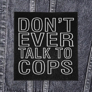 Może przedstawiać: Czarna kwadratowa naszywka z białym obramowanym tekstem o treści "DON'T EVER TALK TO COPS". Naszywka jest wyświetlana na ciemnej dżinsowej kurtce.
