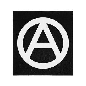 May include: A square-shaped fabric patch featuring a black background with a white circular anarchy symbol centered on the surface. The design consists of a capital letter A enclosed within a circle, rendered in a bold, high-contrast graphic style.
