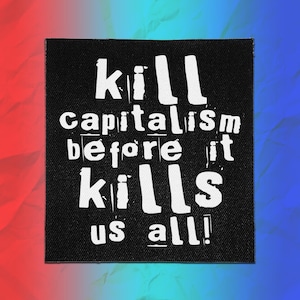 以下が含まれることがあります： 「kill capitalism before it kills us all!」という白い文字がプリントされた正方形の黒い布製ワッペン。文字はかすれた手書き風のデザインで、黒い背景素材全体に織り目がはっきりと見えています。