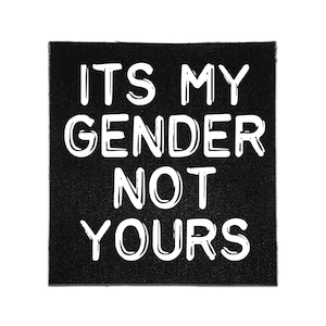 Könnte beinhalten: Ein quadratischer schwarzer Stoffaufnäher mit dem weißen Text ITS MY GENDER NOT YOURS in einer fetten, handgezeichneten Schriftart. Der Aufnäher hat eine sichtbare Webstruktur und saubere Kanten, was ein kontrastreiches Design ergibt.