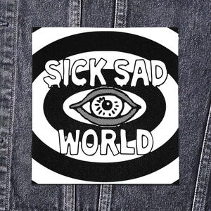 Puede incluir: Un parche cuadrado en blanco y negro con la frase "SICK SAD WORLD". El diseño incluye un ojo en el centro, rodeado de círculos concéntricos. El parche es probablemente de tela y está diseñado para coser o pegar.