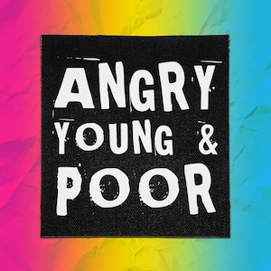 Può includere: Una toppa quadrata in tessuto nero con il testo bianco ANGRY YOUNG & POOR stampato in un carattere sans-serif audace e usurato. La scritta è disposta su tre righe distinte, centrate sul materiale scuro e testurizzato della toppa.