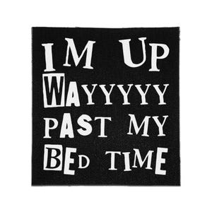 Pode incluir: Um emblema de tecido quadrado preto com o texto branco que diz I M UP WAYYYYY PAST MY BED TIME. As letras estão dispostas em quatro linhas com uma fonte sem serifa em negrito, criando um design de alto contraste na superfície têxtil escura.