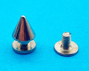 May include: A silver-toned metal cone stud fastener consisting of two separate pieces. One piece features a pointed conical top attached to a flat circular base, while the second piece is a flat circular base with a threaded metal screw post.