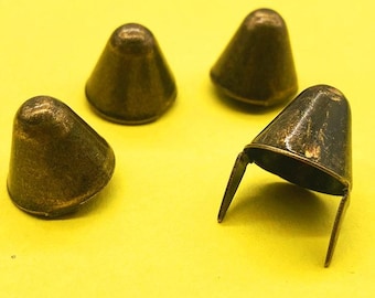 May include: Four cone-shaped metal studs with an antique bronze finish. Each stud features a rounded top and two prongs extending from the base for attachment. The metal surface displays a weathered, dark metallic texture with subtle highlights.