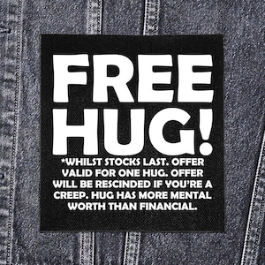 Może przedstawiać: Czarna kwadratowa naszywka z napisem "FREE HUG!" dużymi białymi literami. Poniżej mniejszy biały tekst brzmi: "*WHILST STOCKS LAST. OFFER VALID FOR ONE HUG. OFFER WILL BE RESCINDED IF YOU'RE A CREEP. HUG HAS MORE MENTAL WORTH THAN FINANCIAL."
