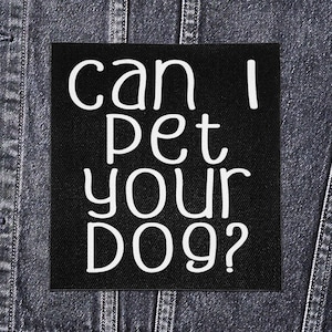 Może przedstawiać: Czarna kwadratowa naszywka z białym napisem "can I pet your dog?". Naszywka jest przyszyta do ciemnej dżinsowej kurtki. Tekst jest w zabawnym, odręcznym stylu.
