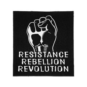 May include: A square black fabric patch featuring a white graphic illustration of a raised fist. Below the fist, the text RESISTANCE REBELLION REVOLUTION is printed in a bold, white, sans-serif font. The patch has a visible woven texture.
