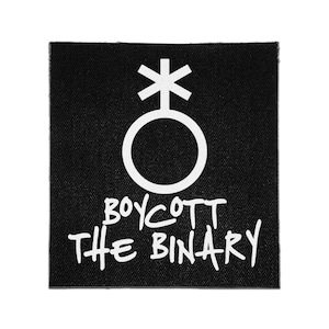 May include: A square black fabric patch featuring a white graphic of a gender symbol with an asterisk at the top. Below the symbol, the text BOYCOTT THE BINARY is printed in a bold, white, hand-lettered style font against the black background.