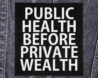 May include: Black square patch with white text that reads "PUBLIC HEALTH BEFORE PRIVATE WEALTH." The patch is sewn onto a denim jacket. The text is in a bold, sans-serif font.