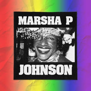 May include: A square black and white fabric patch featuring a halftone portrait of Marsha P. Johnson. The text MARSHA P is printed in white block letters above the portrait, and the text JOHNSON is printed in white block letters below it.