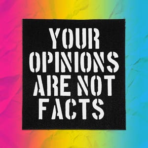 May include: A square black fabric patch featuring the white stencil-style text "YOUR OPINIONS ARE NOT FACTS" printed in a bold, sans-serif font. The patch has a visible woven texture and clean, straight edges, presenting a high-contrast design.