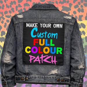 May include: A dark denim jacket with a black patch displaying the text "MAKE YOUR OWN Custom FULL COLOUR PATCH" in vibrant colours. The jacket has a distressed look with button fastenings and worn details.