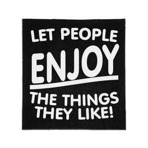May include: A square black fabric patch featuring white embroidered text that reads LET PEOPLE ENJOY THE THINGS THEY LIKE! with a horizontal line separating the word ENJOY from the rest of the text in a bold, sans-serif font style.
