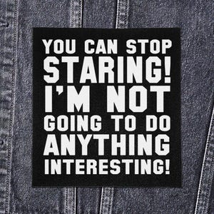 Może przedstawiać: Czarna kwadratowa naszywka z białym tekstem: "YOU CAN STOP STARING! I'M NOT GOING TO DO ANYTHING INTERESTING!" Naszywka jest pokazana na dżinsowej kurtce.