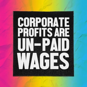 May include: A square black fabric patch featuring the white text "CORPORATE PROFITS ARE UN-PAID WAGES" in a bold, sans-serif font. The patch has a visible woven texture and is set against a vibrant, multi-colored rainbow gradient background.